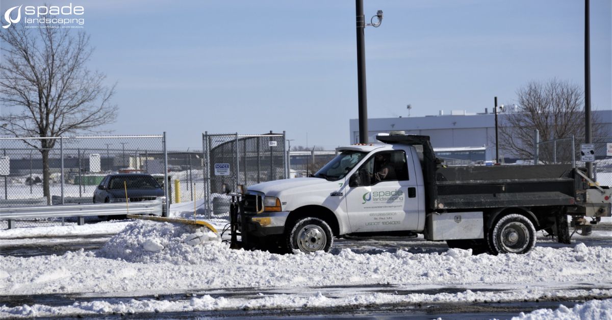 side view of a white truck plowing snow - Spade Landscaping commercial snow plowing services