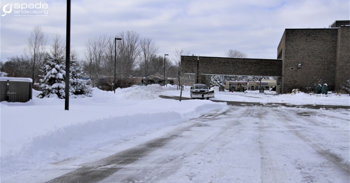 front view of a white truck in snow covered lot - Spade Landscaping commercial snow plowing services