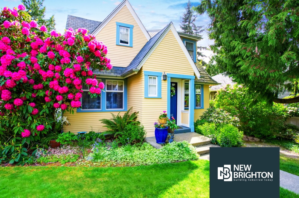 exterior of a yellow house with bright pink flowers  - Spade Landscaping Landscaping New Brighton MN
