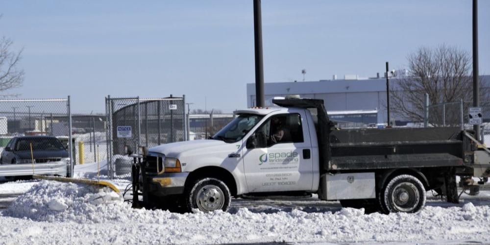 side view of a truck plowing snow - Spade Landscaping commercial snow plowing services