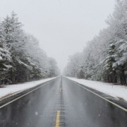 empty road with snow covered trees on both sides - Spade Landscaping commercial snow plowing services