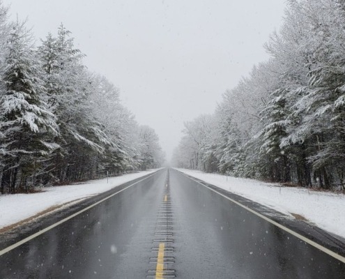 empty road with snow covered trees on both sides - Spade Landscaping commercial snow plowing services