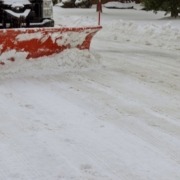 white truck with a red plow driving through snow - Spade Landscaping commercial snow plowing services